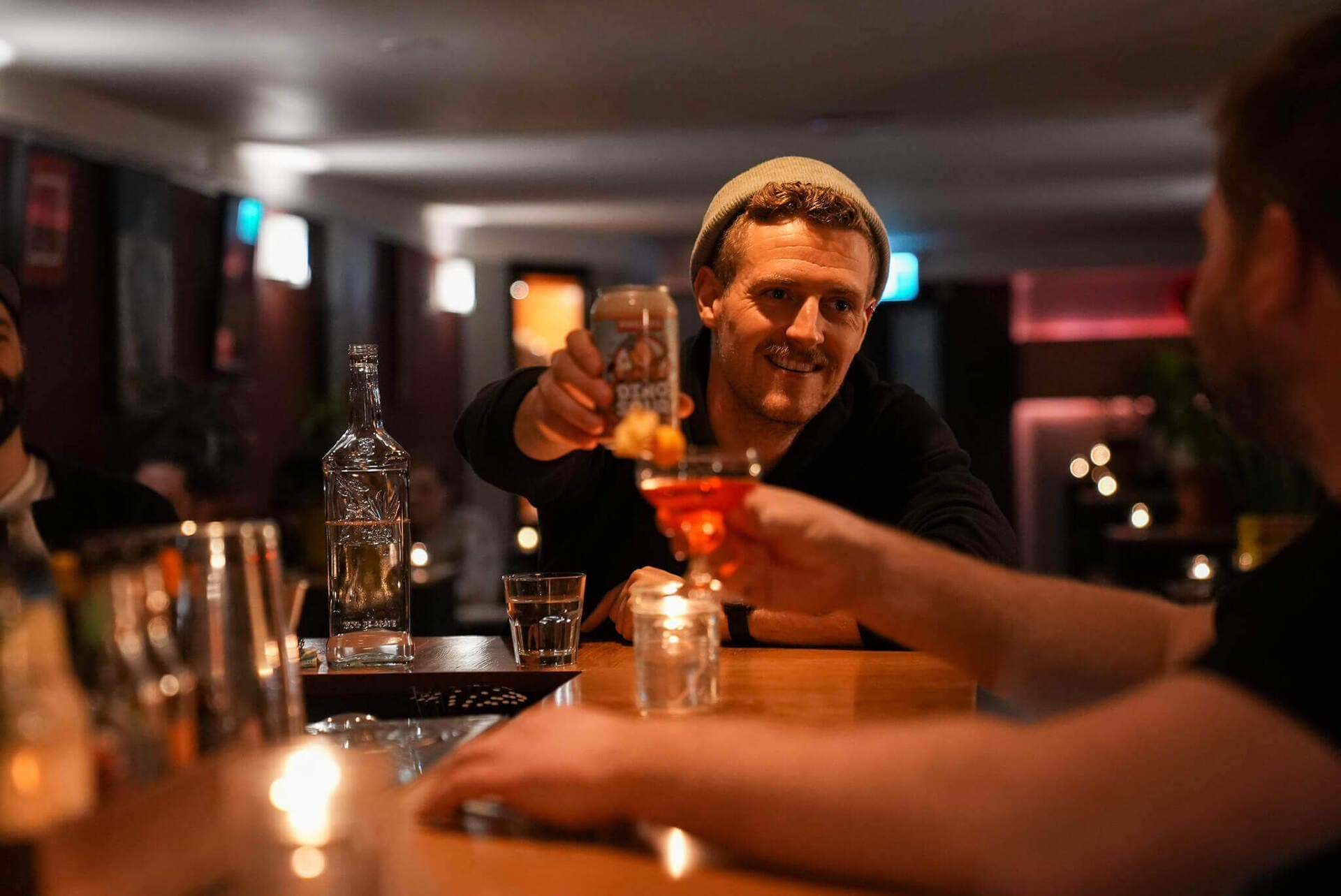 Friends raising craft cocktails in the warm candlelight at Cenote